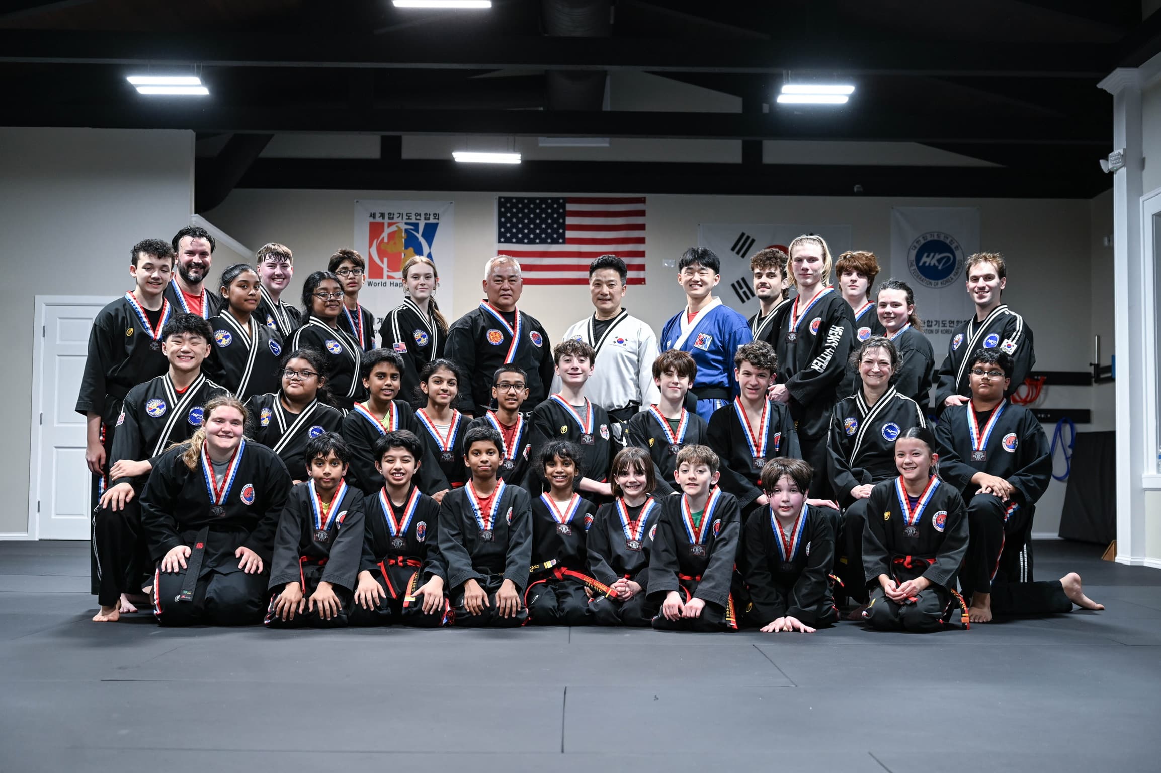 Around 28 students and instructors posed together on the gray mat