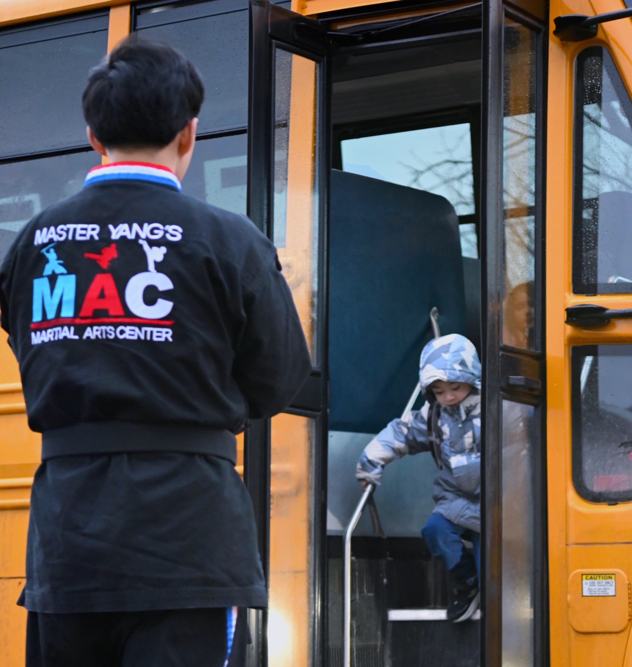 Instructor helping a child down from a yellow school bus