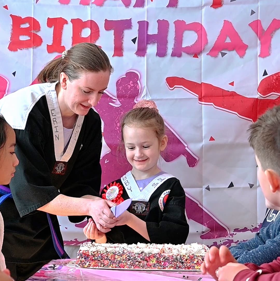 Instructor helping a young girl cut a birthday cake