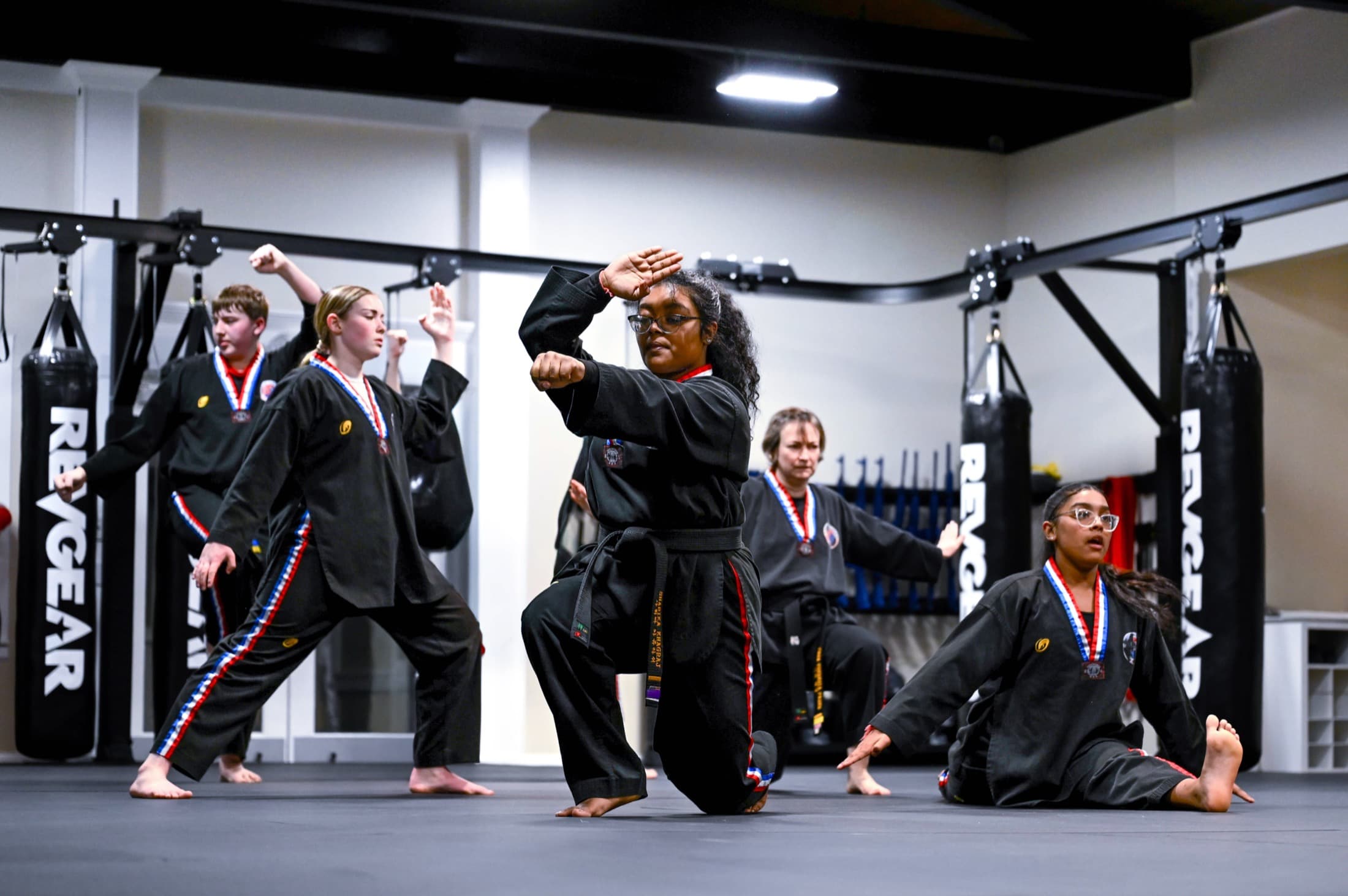 Five students holding a low stance mid-form in unison