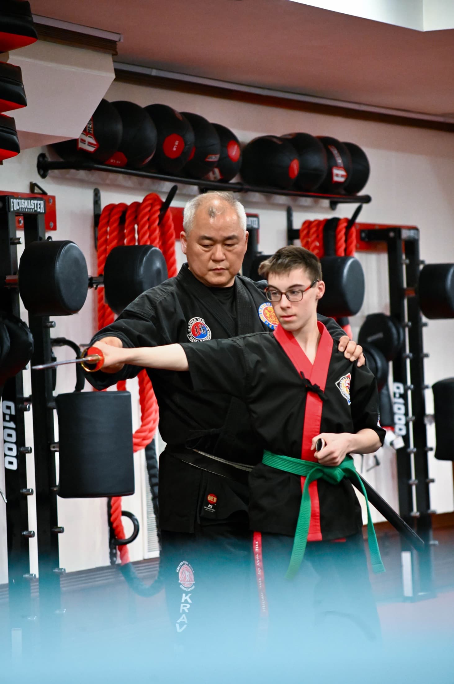 Grandmaster Yang guiding a student's punch on a striking machine